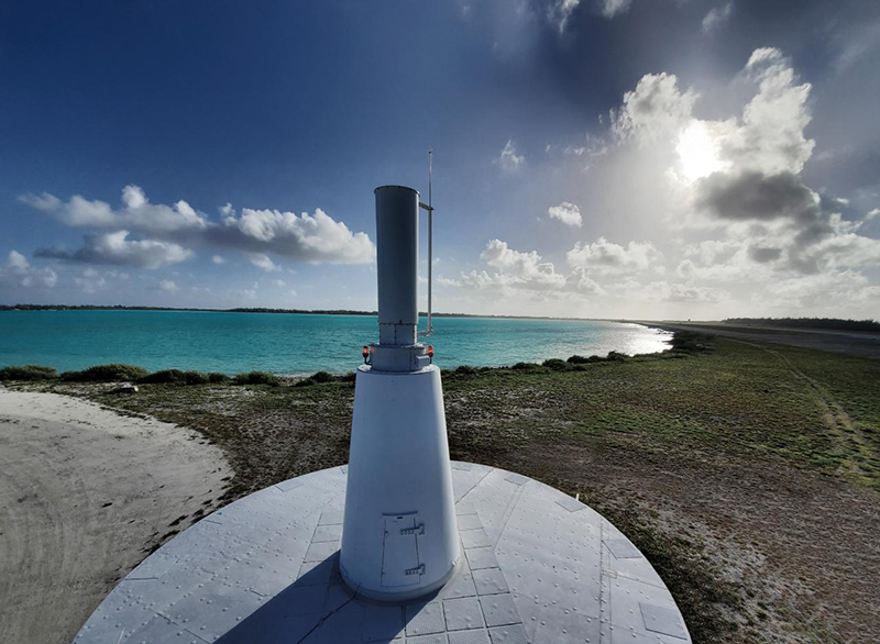 A TACAN system rises out of the ground, a white pillar of concrete with radar technology at the top.